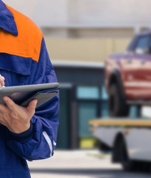 Close up of insurance officer using electronic pen to recording data of broken pickup car on tablet while prepare for transporting to garage after accident on the road